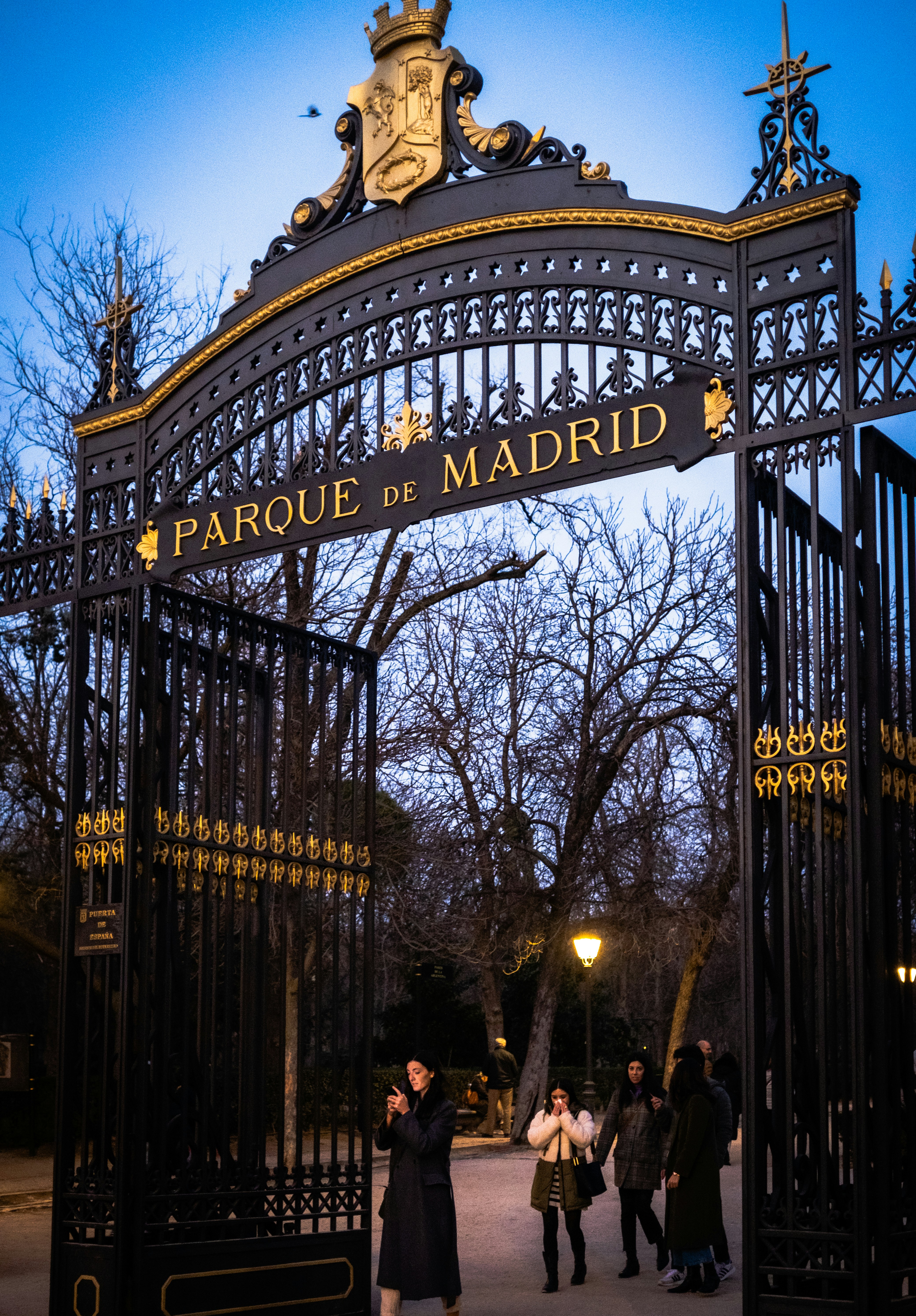 a group of people walking under a wrought iron gate