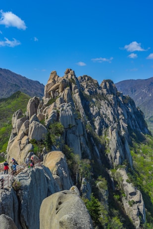 Kacper Denisiuk guiding a small group along a rocky alpine ridge with panoramic views.