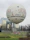 Large advertising inflatable shaped like a product logo at a busy outdoor fair.