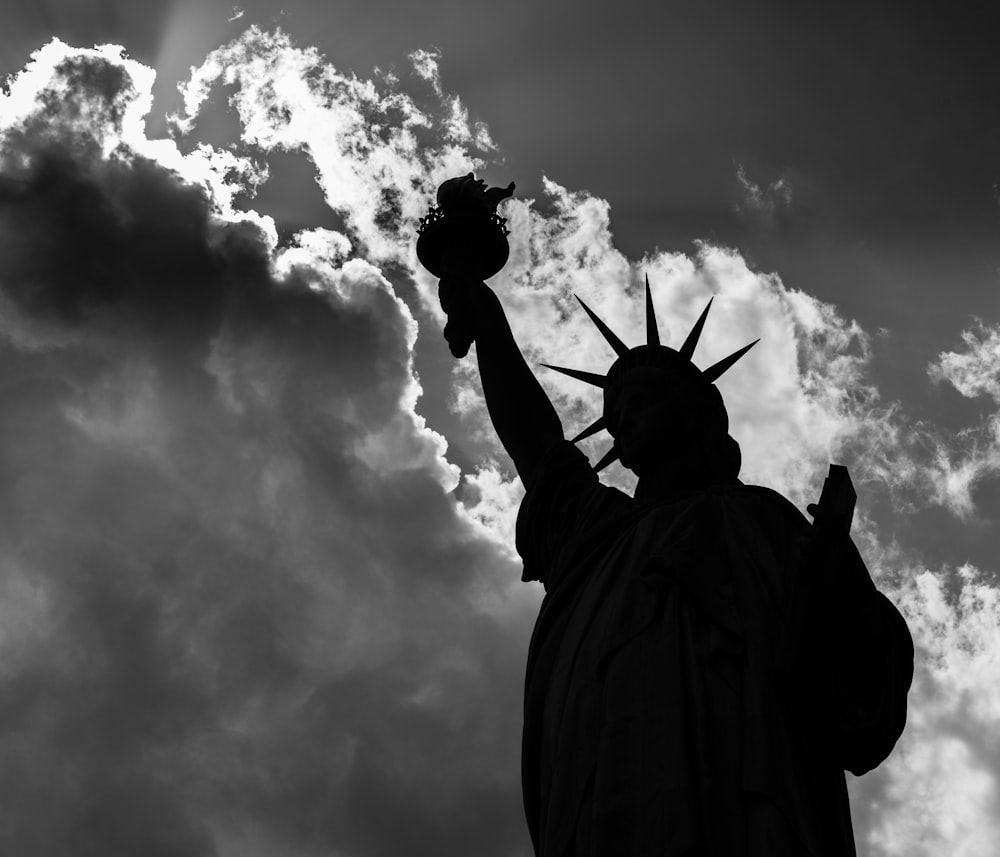 the statue of liberty is silhouetted against a cloudy sky