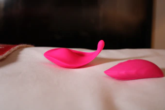 A hand holding a flexible, silicone dildo with a soft-focus background.