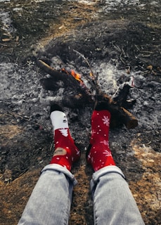 A person wearing winter cotton socks while sitting by a fireplace.