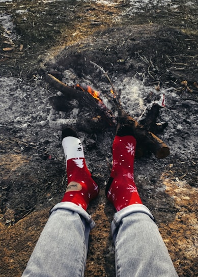 A person wearing winter cotton socks while sitting by a fireplace.