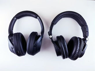 A pair of black over-ear headphones is placed against a white background. The headphones have thick, padded ear cups and an adjustable headband, with one labeled 'L' and the other 'R' for left and right sides.