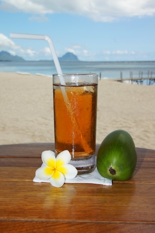 An iced hibiscus tea with slices of fresh lime and mint leaves on a sunny patio table.