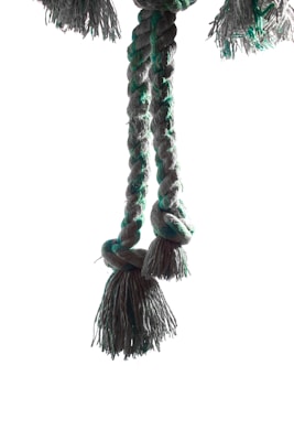 A thick rope tied in a knot with frayed ends hanging down. The rope is braided and features a combination of green and gray colors.