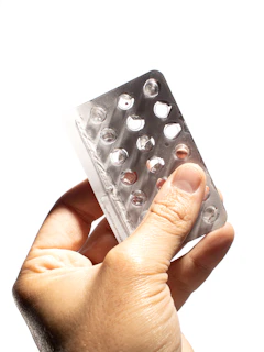 Hands holding a transparent blister pack of pills with the Novomark Pharma logo subtly visible