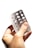 A hand is holding an empty blister pack with multiple circular compartments. The packaging is made of transparent plastic and silver foil, and it appears to be missing several tablets.