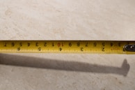 A person measuring their waist with a tape measure in a bright room.