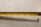 A yellow tape measure is extended across a light-colored surface. The tape displays both metric and imperial measurements. Numbers and markings are clearly visible, with shadows cast on the background.