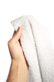 A hand easily tearing off a sheet from a disposable face towel roll.