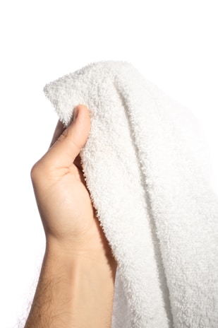 A hand is holding a fluffy, white towel against a plain white background.