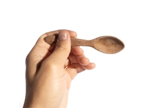 Close-up of a chef's hand holding a wooden spoon over a rustic kitchen counter.