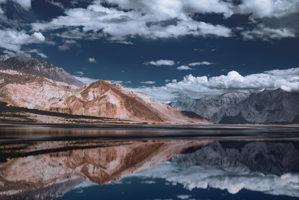 um lago cercado por montanhas sob um céu nublado