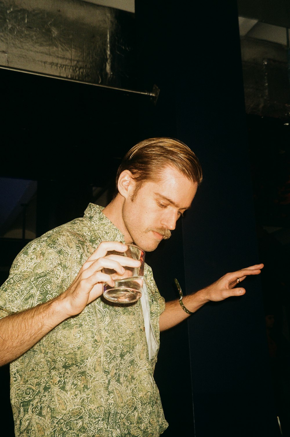 a man in a green shirt holding a wine glass