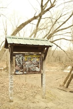 Close-up of a wooden sign nailed with screws, featuring chaotic graffiti style text.