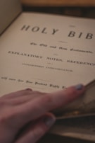 Close-up of hands gently holding an open Bible with worn pages.