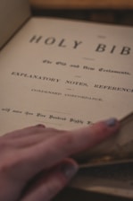 Close-up of hands gently turning pages of a weathered religious manuscript.