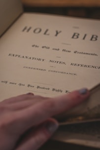 Close-up of hands gently turning pages of a weathered religious manuscript.