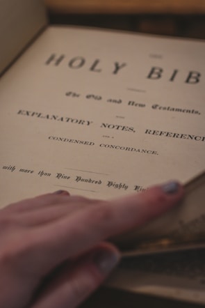 Close-up of hands turning pages in a well-worn Bible during an online study.