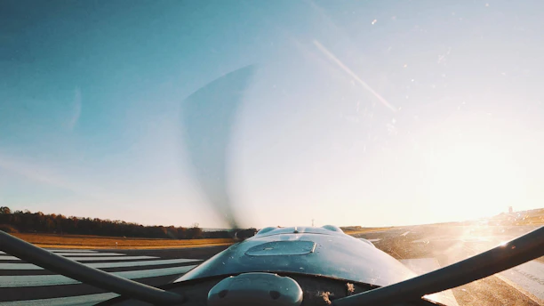 A scenic view of a plane taking off into a clear blue sky at sunset.