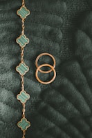 Stacked gold bracelets with dark green accents, photographed with soft natural light.