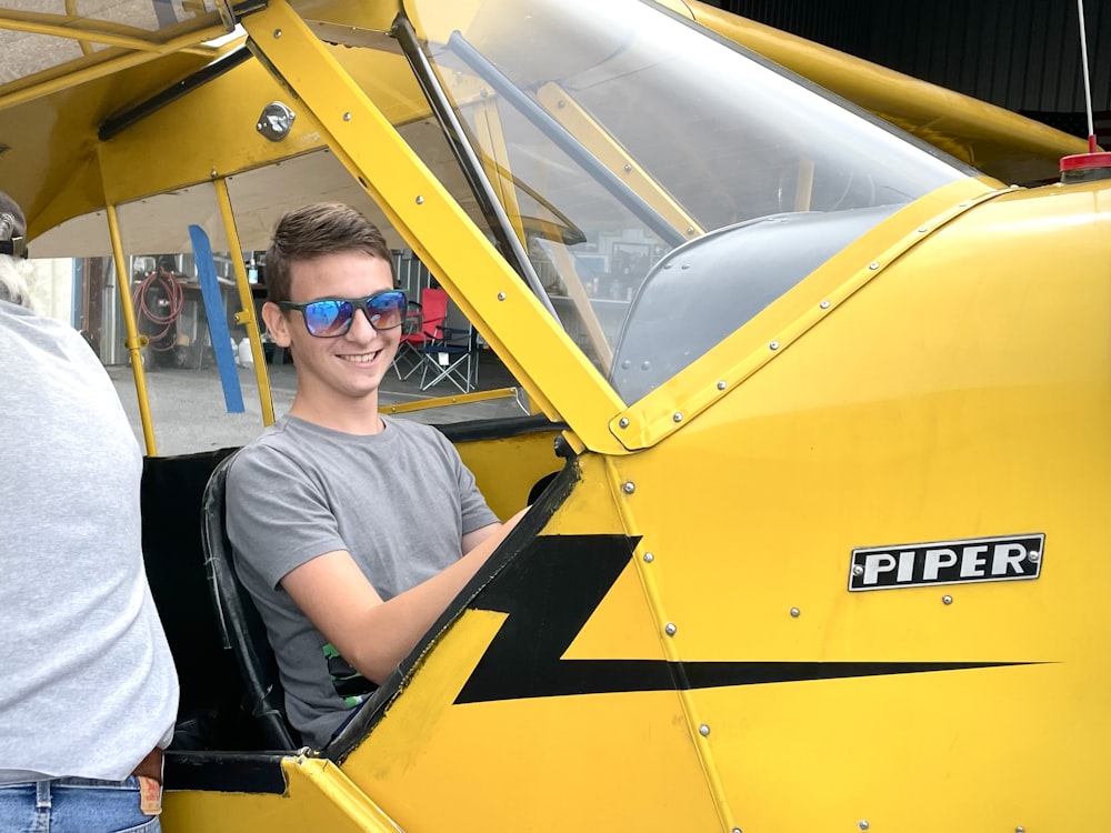 a man sitting in the cockpit of a yellow plane