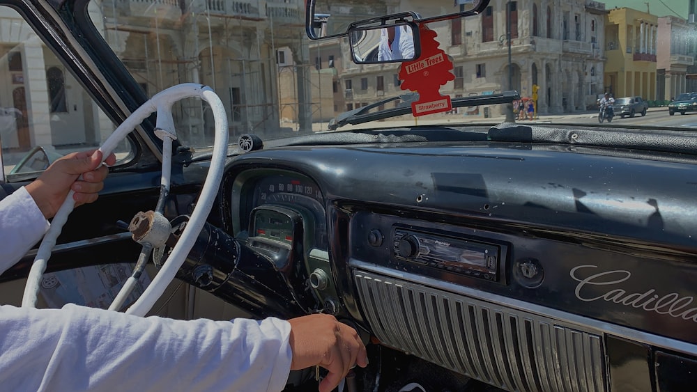 a woman driving a classic car down a street