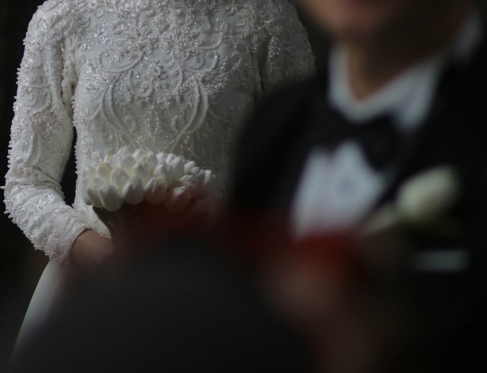 a woman in a white dress standing next to a man in a tuxedo