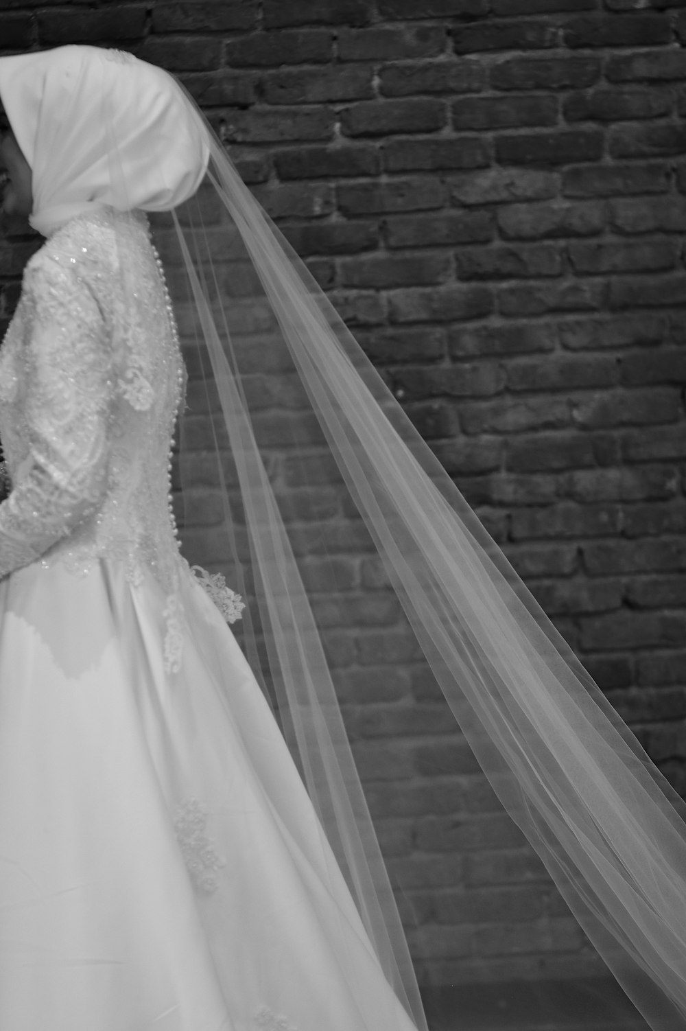 a bride and groom standing in front of a brick wall