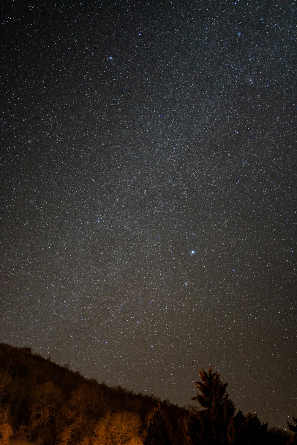 the night sky with stars above a hill