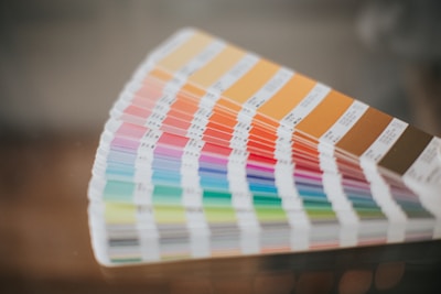 A fan of color swatches arranged in a gradient pattern, displaying a wide range of hues from warm oranges and browns to cool blues and greens. The swatches are shown in a curved formation, with labels indicating different shades.