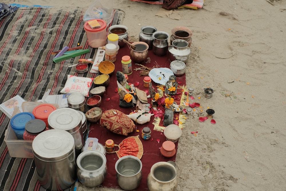 a blanket on a beach covered in pots and pans