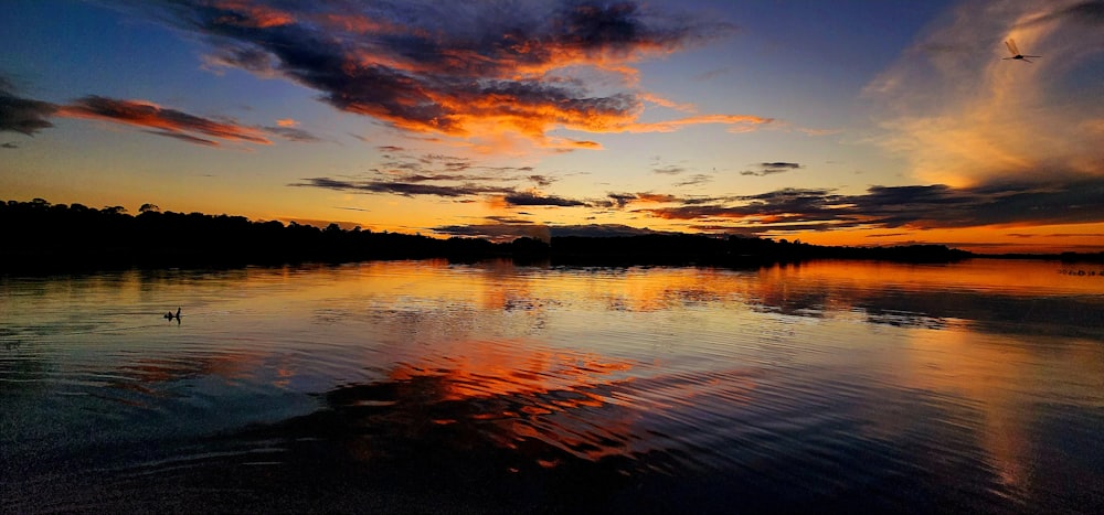 a sunset over a body of water with clouds in the sky