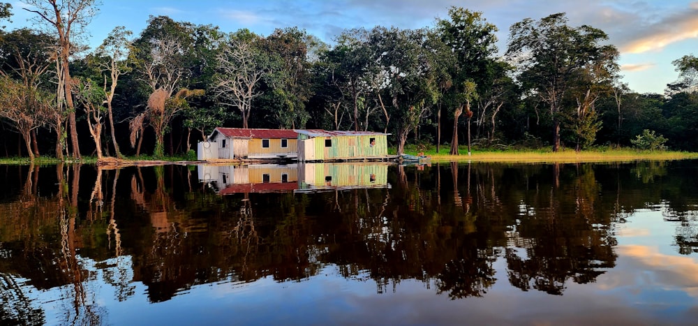 uma casa sentada no topo de um lago ao lado de uma floresta