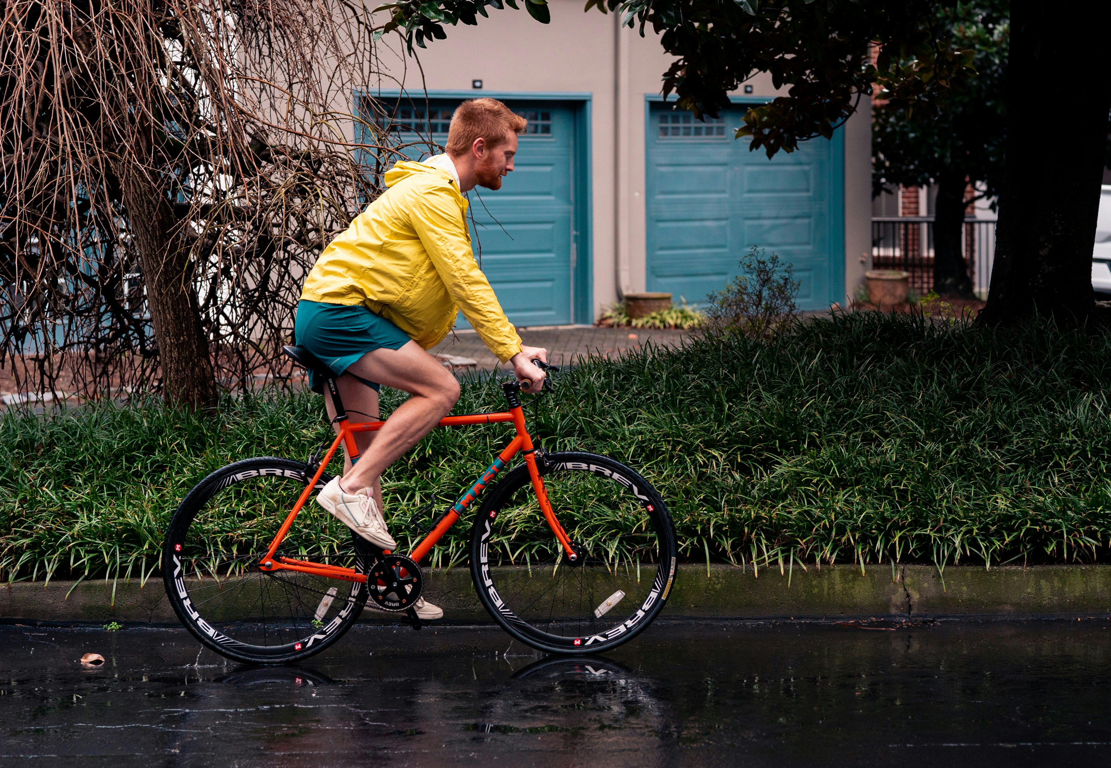 a man riding a red bike down a rain soaked street