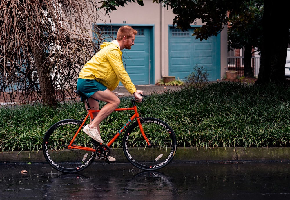 a man riding a red bike down a rain soaked street