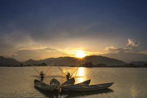 A cheerful family of three fishing together by a peaceful lake at sunset.