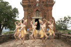 Traditional Sri Lankan dancers in colorful costumes performing under ancient temple arches.