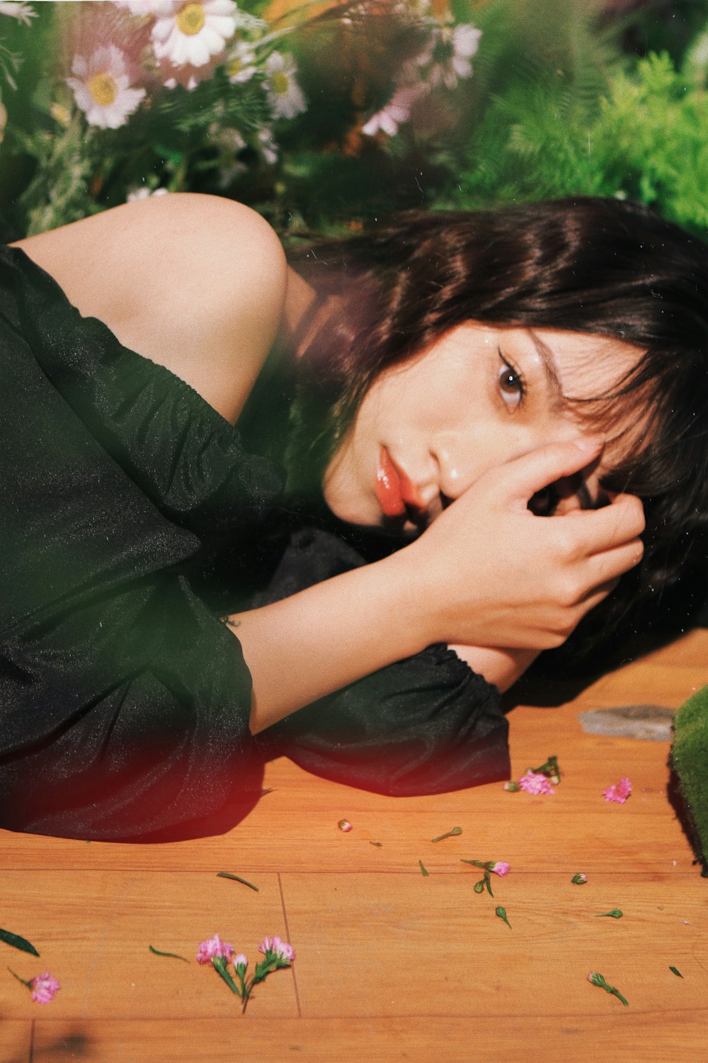 a woman laying on a wooden floor next to flowers