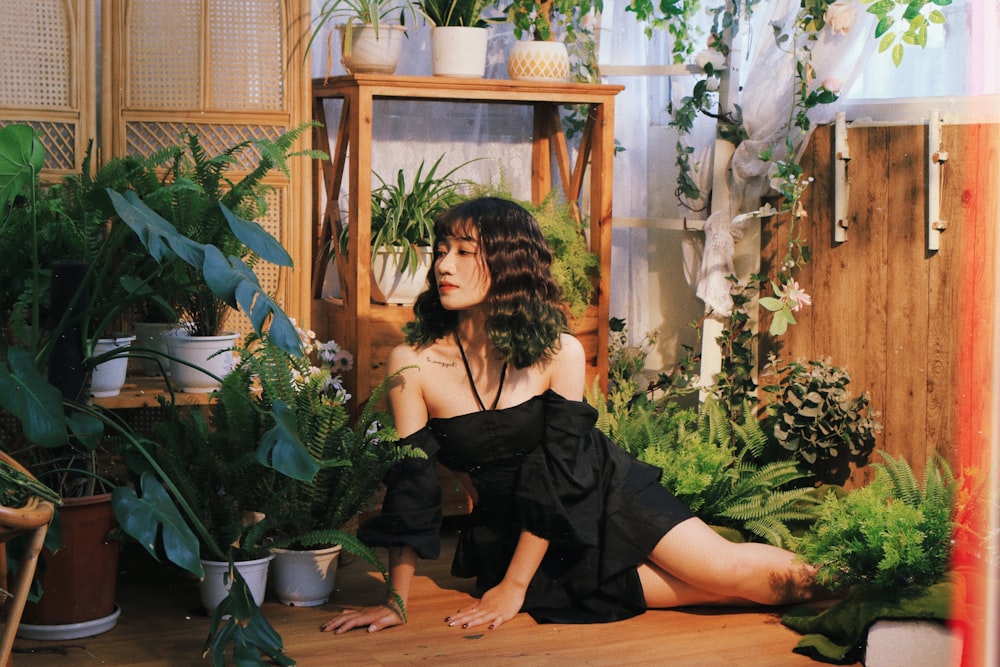 a woman sitting on the floor surrounded by potted plants