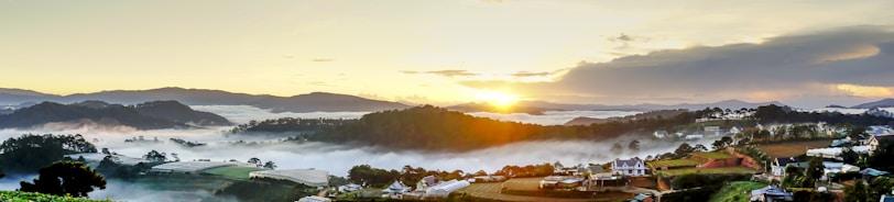 A misty sunrise over the rolling hills of Meghalaya, dotted with traditional Khasi huts.