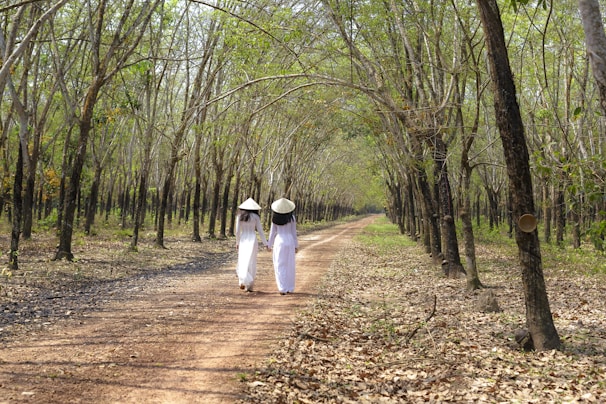 The couple holding hands on a sunlit riverside path in Vietnam