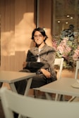 a man sitting at a table in front of a vase of flowers