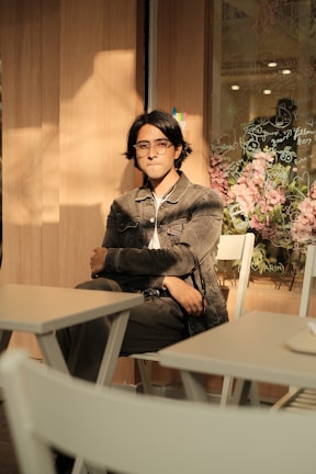 a man sitting at a table in front of a vase of flowers