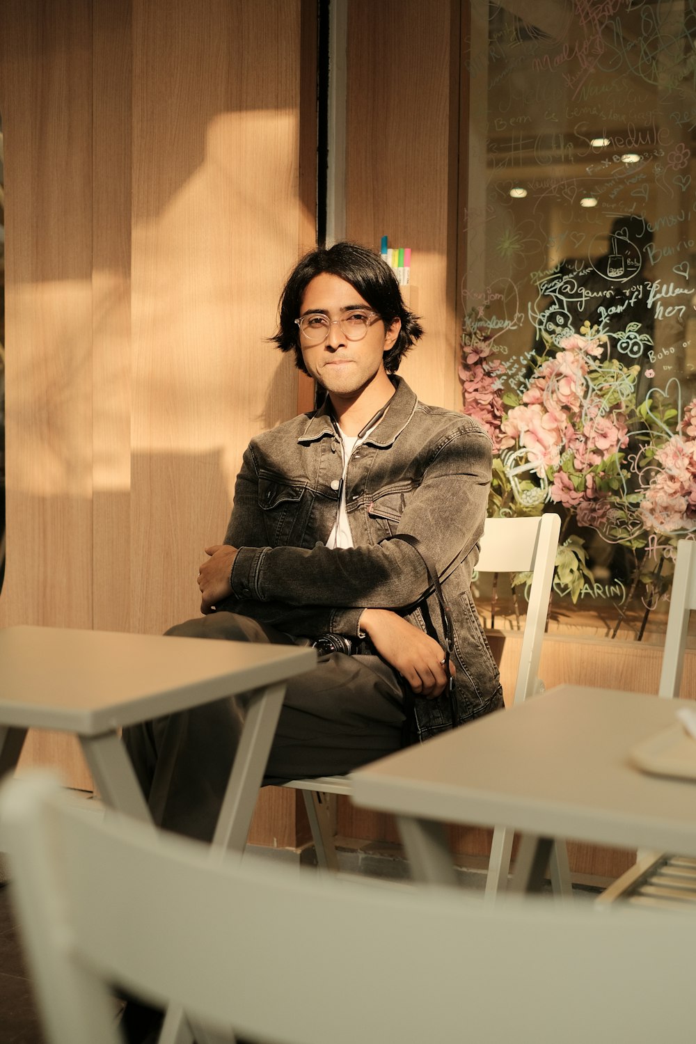 Un homme assis à une table devant un vase de fleurs