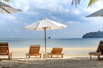 Family relaxing on comfortable beach loungers under bamboo shade structures.