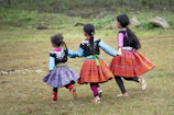 A group of children laughing together, dressed in colorful, handcrafted cultural attire.