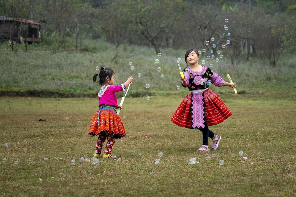two little girls playing with bubbles in a field
