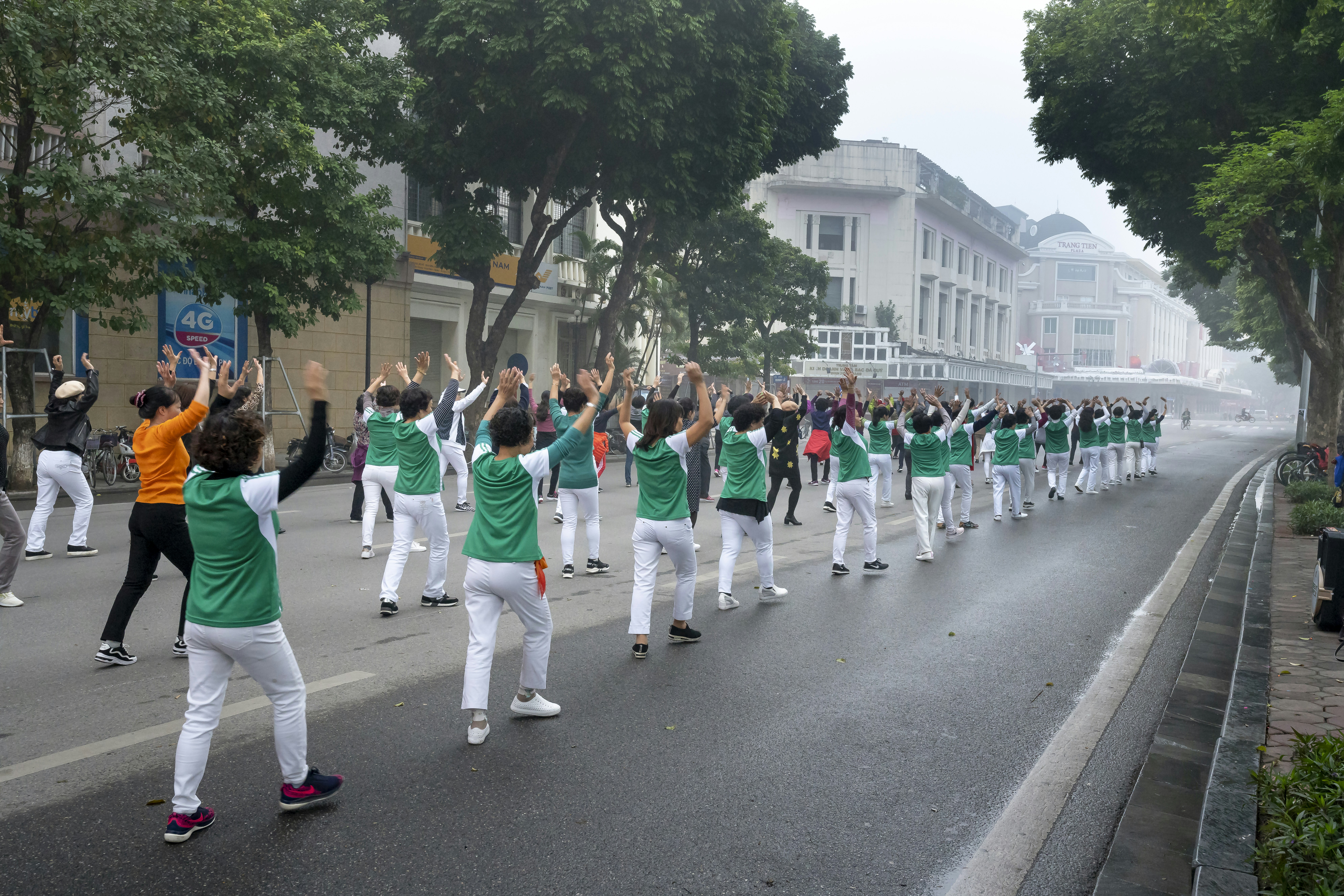 a group of people in green and white outfits marching down a street